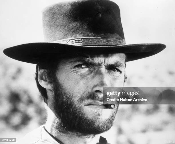 American actor Clint Eastwood squints while smoking a cigarette between his teeth in a still from director Sergio Leone's film 'The Good, The Bad,...