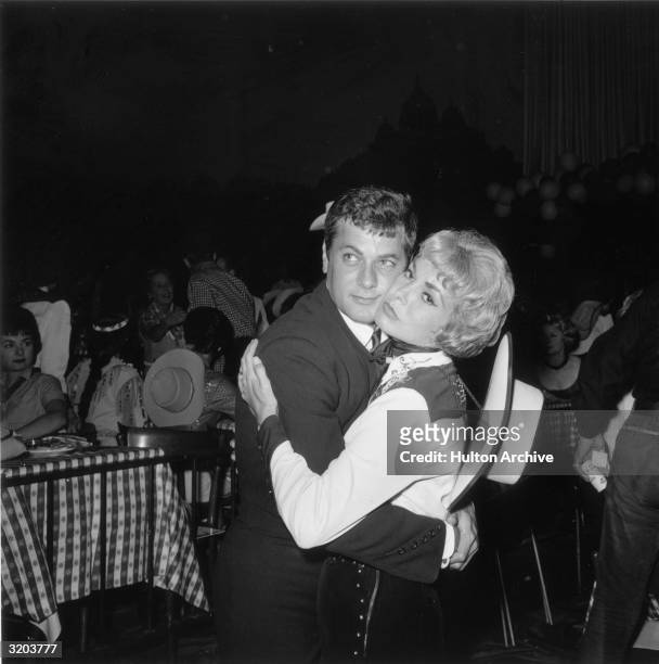 Married American actors Tony Curtis and Janet Leigh embrace while dancing at a costume party to benefit mentally retarded children, possibly a SHARE...