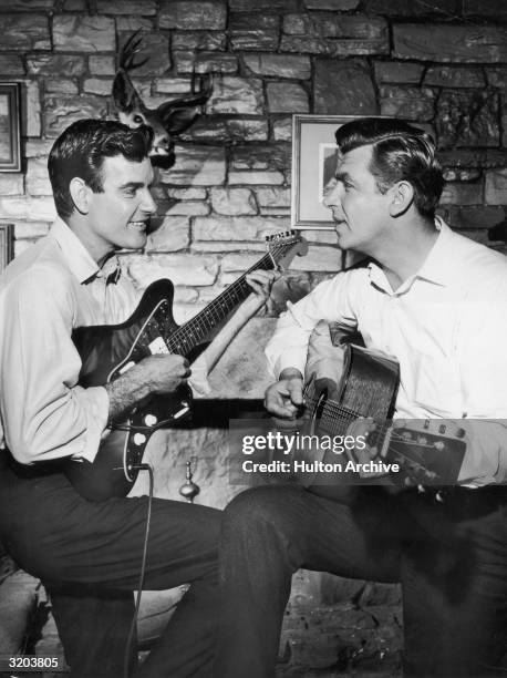 American actors James Best and Andy Griffith play a guitar duet while sitting in a living room in a publicity still from the television series, 'The...