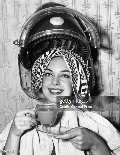 Louise Crous, Miss South Africa 1963, drinks a cup of coffee as she gets her hair done in preparation for the Miss World beauty pageant, London.