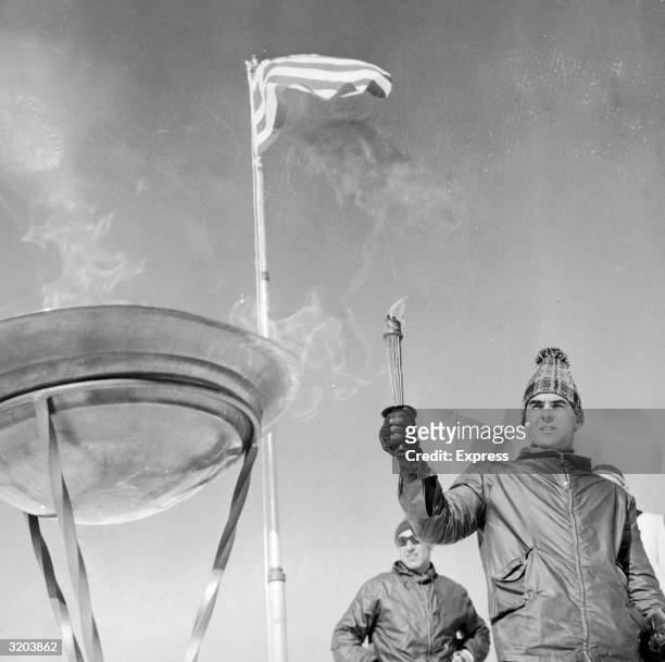 Skier uses a torch to light the Olympic flame atop snowcapped peak of Mount Olympus, mythical home to the Greek gods, prior to the commencement of...
