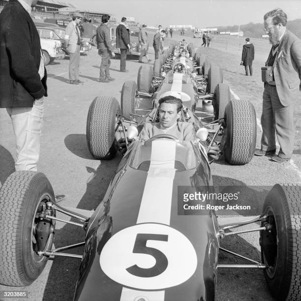 English racing driver Jim Clark relaxes at the wheel of a Lotus Climax at Brands Hatch before clocking-up 100.21mph for the 2.65 mile circuit. This...