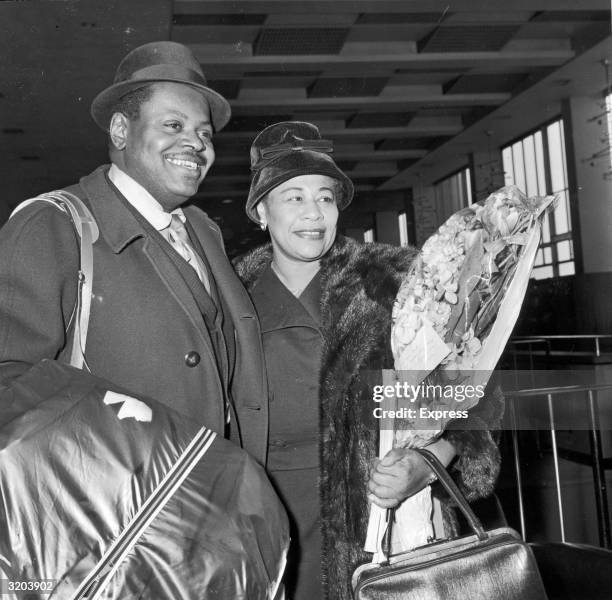 Canadian jazz pianist Oscar Peterson and American jazz singer Ella Fitzgerald arriving at Festival Hall, London, England. Fitzgerald wears a long fur...