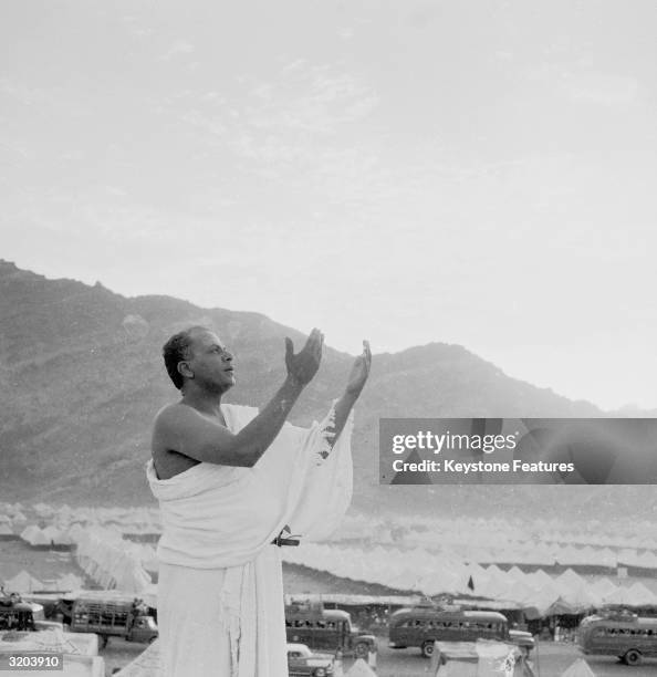 Muslim raises his hands in prayer at Mecca, the holy shrine of Islam in Saudi Arabia. The city of pilgrims' tents at the foot of Mount Ararat, can be...