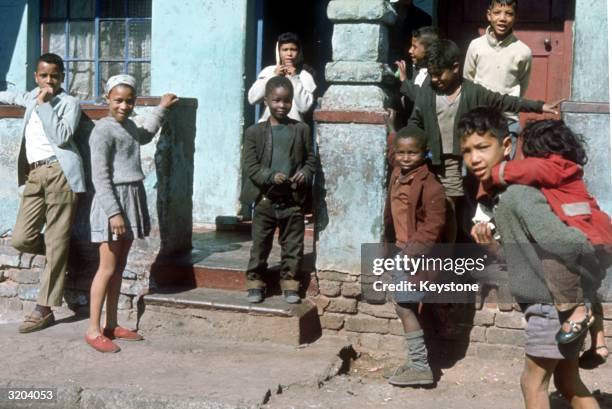South Africans gather outside their homes. The government claims that many blacks own their own homes, the truth is they do not and are forbidden to...