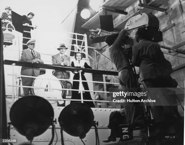 American actors Clark Gable and Joan Crawford lean on the railing of a ship's deck, recreated on the set of director W.S. Van Dyke's film, 'Forsaking...