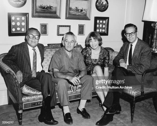 French-born director William Wyler and American actor Shirley MacLaine are flanked by film producer brothers Harold and Walter Mirisch on the set of...