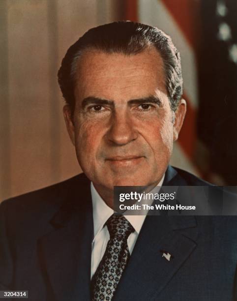 Headshot portrait of 37th American president Richard M. Nixon , wearing a U.S. Flag lapel pin, smiling in front of a U.S. Flag. Nixon's presidency...
