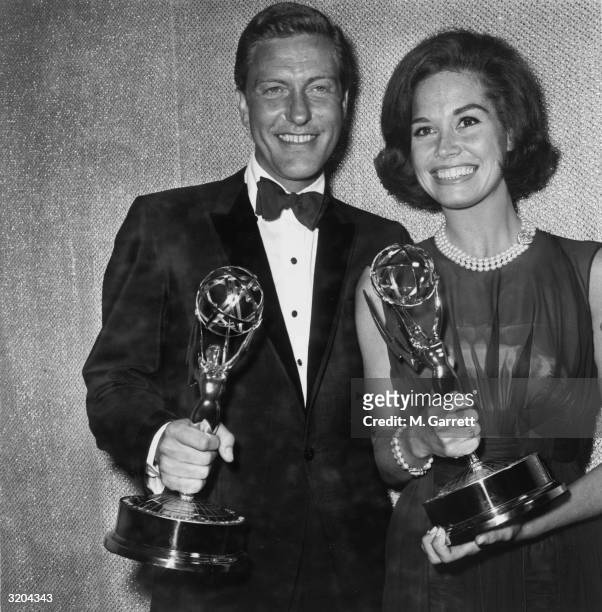 American actors Dick Van Dyke and Mary Tyler Moore smile while holding the Emmy Awards they won for Best Actor and Actress for the television series,...