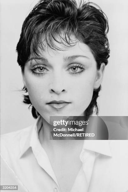 Headshot of American pop singer Madonna wearing an open-necked blouse with short, dark hair, New York City, Spring 1979.