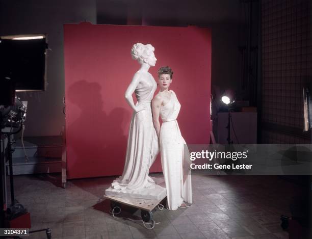 Full-length portrait of American actor Ava Gardner leaning on a statue of herself as Venus, the Roman goddess of love, on the set of director William...