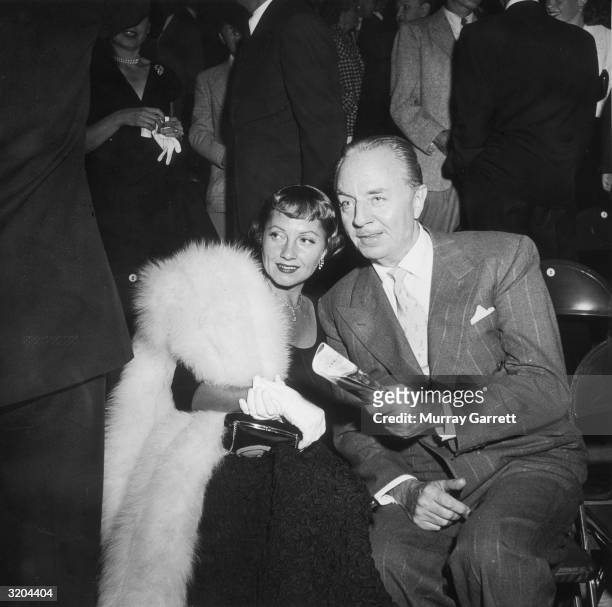 American actor William Powell sits on folding chairs with his wife, American actor Diana 'Mousie' Lewis , during an Ice Follies party, Los Angeles,...
