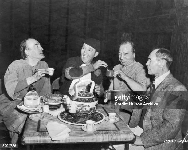 Actors Fred Sweeney, Bing Crosby, Gene Delmont and John 'Skins' Miller drink tea on the set of director Tay Garnett's film, 'A Connecticut Yankee in...
