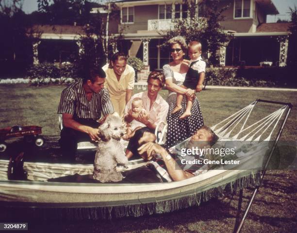 American filmmaker and producer Walt Disney relaxing on a hammock with his family and their pet dog, California. Pictured are Disney's wife, Lillian...