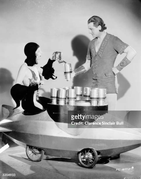 Kay Johnson serves tea to Reginald Denny from a trolley shaped like a dirigible in a scene from 'Madame Satan', directed by Cecil B DeMille.
