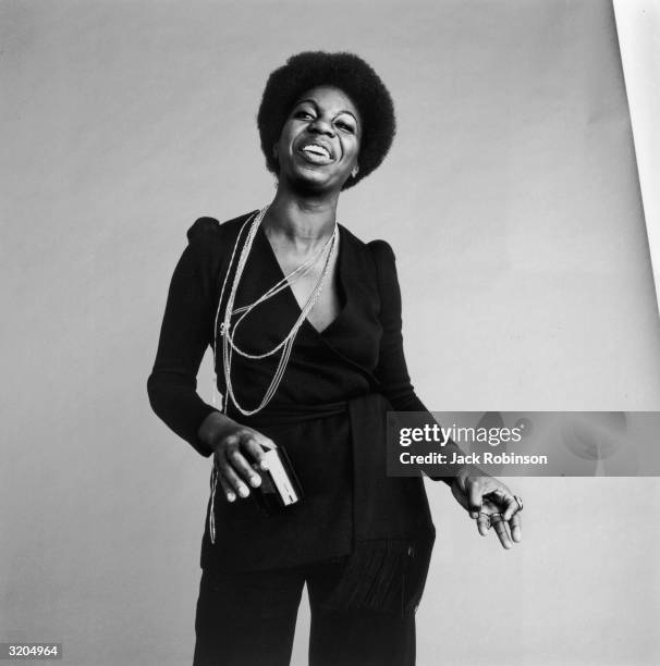 Studio portrait of American vocalist Nina Simone dancing and laughing.