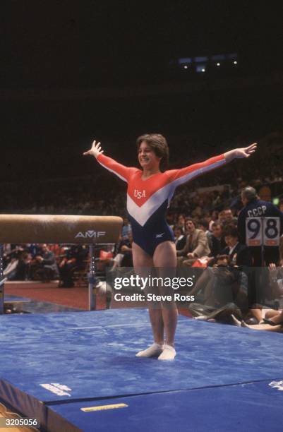 Full-length image of American gymnast Mary Lou Retton smiling while posing on the mat after her dismount from the balance beam at the Summer Olympic...