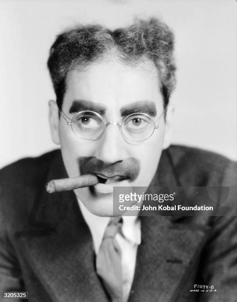 American actor Groucho Marx , with his trademark moustache and glasses.