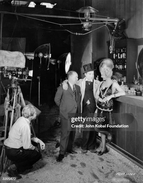 American comic Harry Langdon with his arms around actress Thelma Todd and a male friend in a bar scene from one of his films.