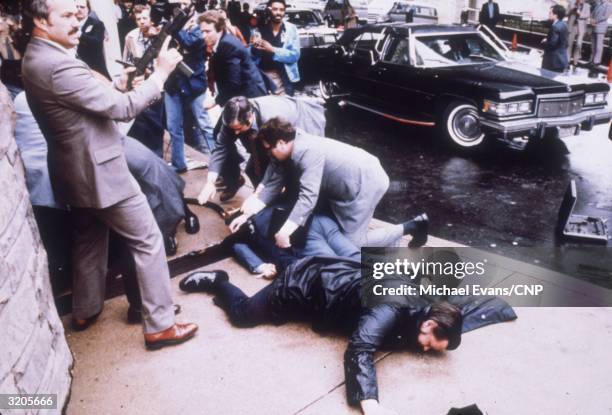 Secret Service men surround President Ronald Reagan and members of his entourage after an assassination attempt outside the Hilton Hotel in...