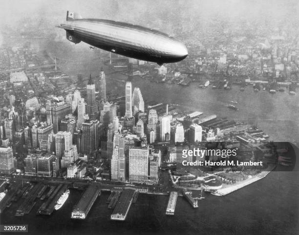 The Hindenburg airship flies over the Hudson River and downtown Manhattan, New York City.
