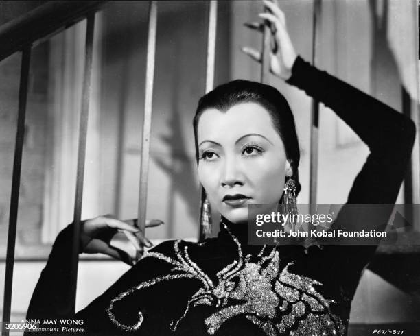 Chinese-American film star, Anna May Wong wearing a dress with a dragon motif in a publicity shot for 'Limehouse Blues', directed by Alexander Hall.