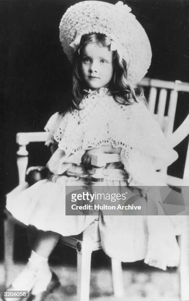 Portrait of German-born actor Marlene Dietrich at age five, sitting in a chair, Germany. She is wearing a light-colored dress with a lace collar and...