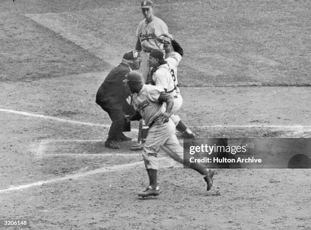 Baseball player Yogi Berra , catcher for the New York Yankees, argues with the umpire over a call after Jackie Robinson stole home plate, during a...