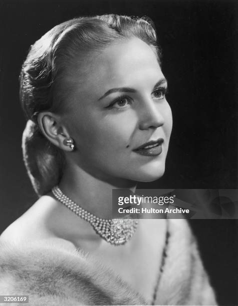 Studio headshot portrait of American singer and actor Peggy Lee wearing a mink stole, a pearl necklace, and pearl earrings.