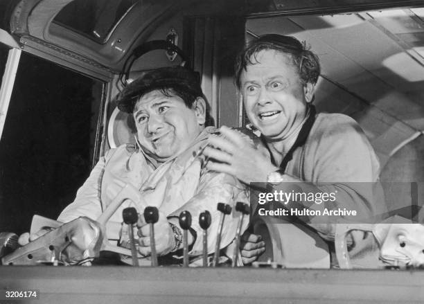 American actors Buddy Hackett and Mickey Rooney panic at the controls of an aircraft in a still from director Stanley Kramer's film 'It's a Mad Mad...