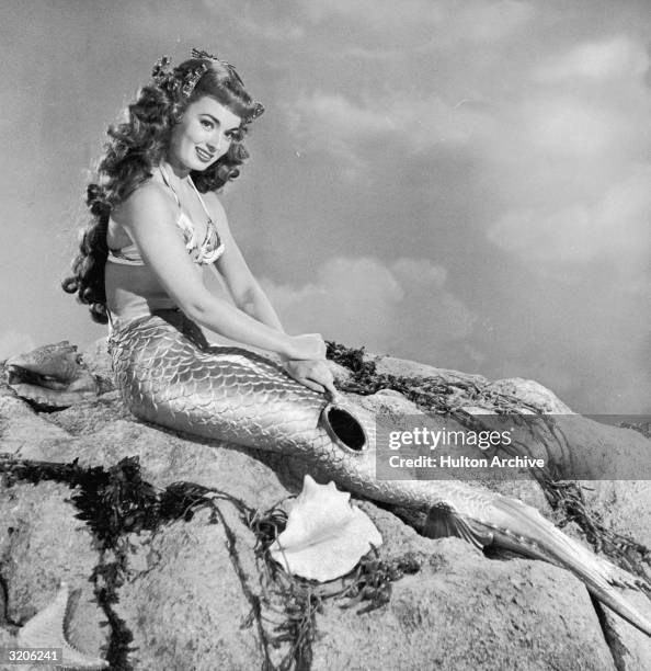 American actor Ann Blyth, wearing a mermaid costume, sits on a rock in a promotional portrait for director Irving Pichel's film, 'Mr. Peabody and the...