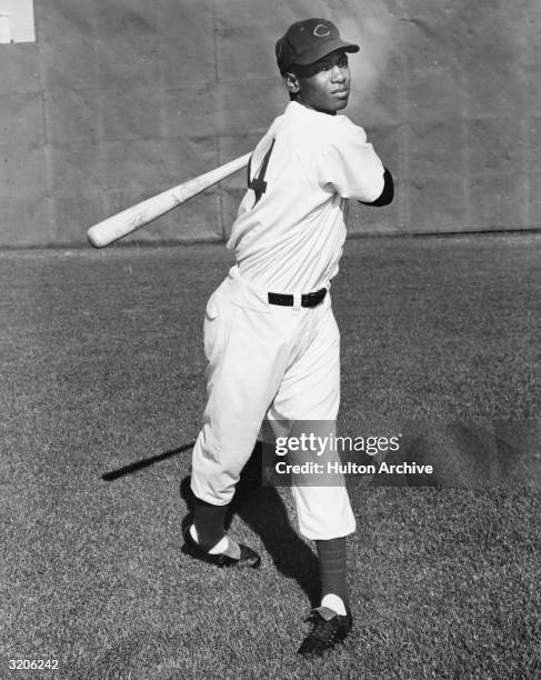 Full-length image of Chicago Cubs shortstop Ernie Banks, wearing his team jersey and cap, swinging a baseball bat on the field.