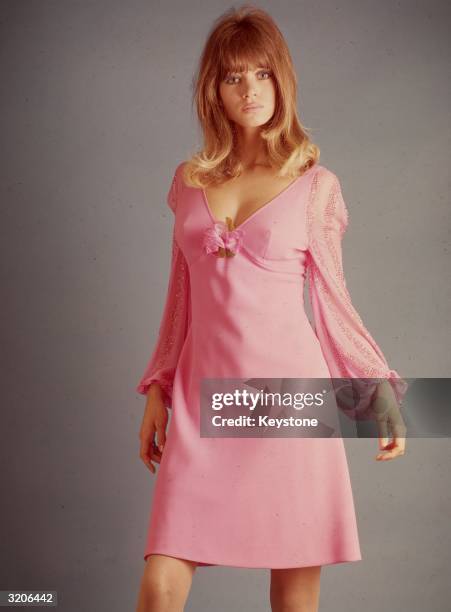 Sixties fashion model wearing a feminine cut mini dress with flared sleeves gathered at the cuffs.