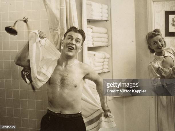 Advertisement shows a man singing next to a shower stall as he dries his back with a towel, while a woman grins at him from the doorway.