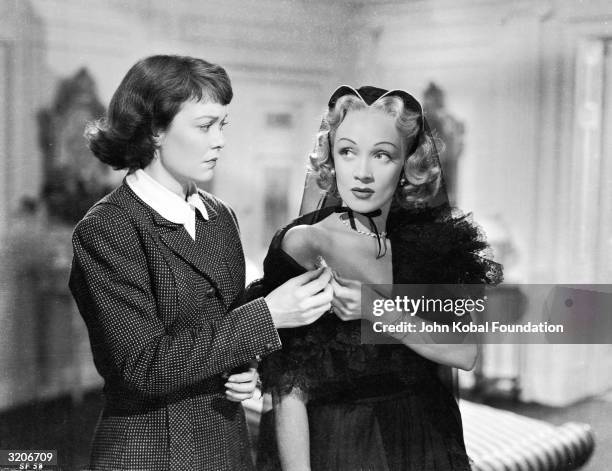 Jane Wyman and Marlene Dietrich share a cigarette in a scene from the murder mystery 'Stage Fright', directed by Alfred Hitchcock.