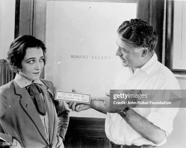 Director Clarence Brown presents a plaque to actress Pauline Frederick on the set of 'Smouldering Fires', in front of Robert Elliott's office door....