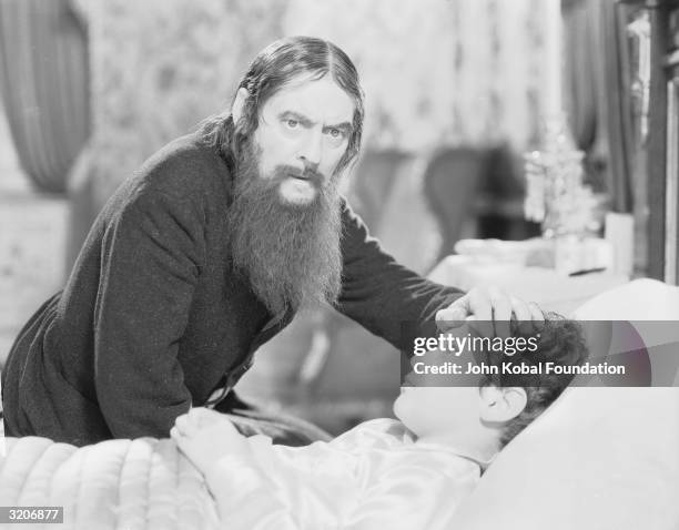 Lionel Barrymore as Rasputin feels the forehead of Tad Alexander as the young Prince Alexis in 'Rasputin and the Empress', directed by Richard...