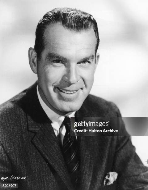 Studio portrait of American actor Fred MacMurray smiling in a jacket and tie.