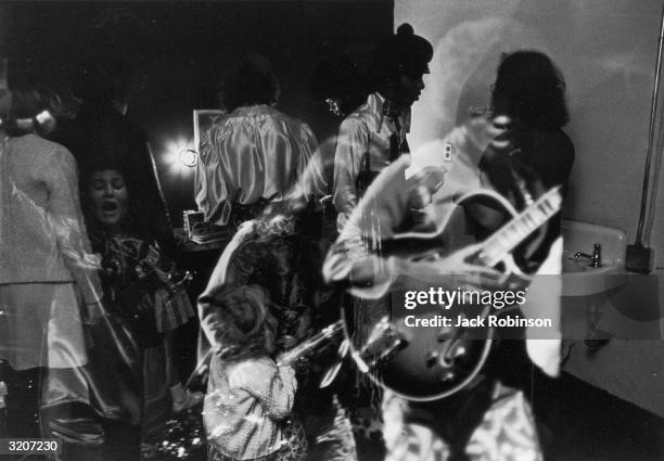 Double-exposed image of American rock, soul and funk singer Sly Stone and band members of his group, Sly and the Family Stone, backstage during a...