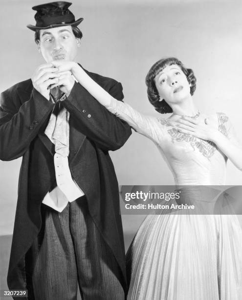 American comedian Sid Caesar, dressed as a hobo, kisses the hand of his costar, actor Imogene Coca , possibly in a promotional portrait for the...