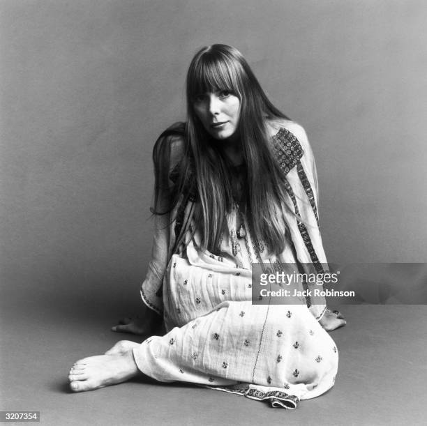 Portrait of American musician Joni Mitchell seated on the floor with her hands behind her. This image is from a shoot for the fashion magazine Vogue....