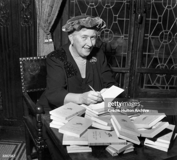 British mystery author Agatha Christie autographing French editions of her books, circa 1950.