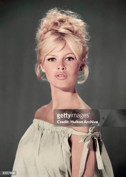 Studio portrait of actor and model Brigitte Bardot wearing a light blue off-the-shoulder dress.