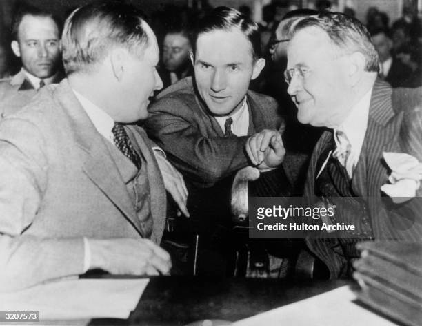 Bruno Richard Hauptmann, later convicted of kidnapping and murdering Charles Lindbergh Jr., confers with his lawyers, Lloyd Fisher and Frederick Pope...