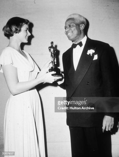 Swedish-born actor Ingrid Bergman presents American actor James Baskett with an Oscar for his portrayal of Uncle Remus in the Disney film Song of the...
