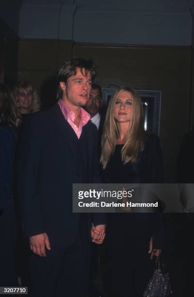 American actors Brad Pitt and Jennifer Aniston holding hands together at Mann Village Theater for the premiere of director David Fincher's film...