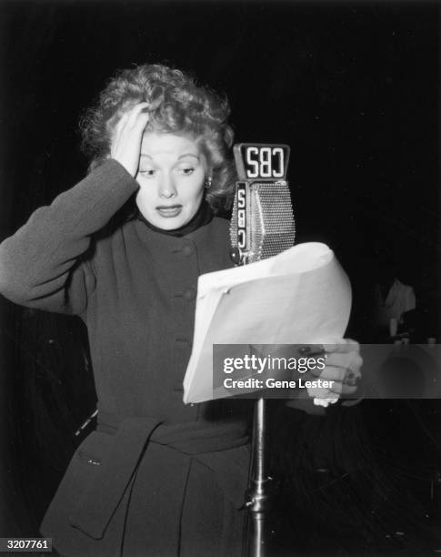 American actor Lucille Ball performing from a script in front of a microphone on the CBS radio show, 'Suspense', USA. Ball is wearing a long-sleeved...