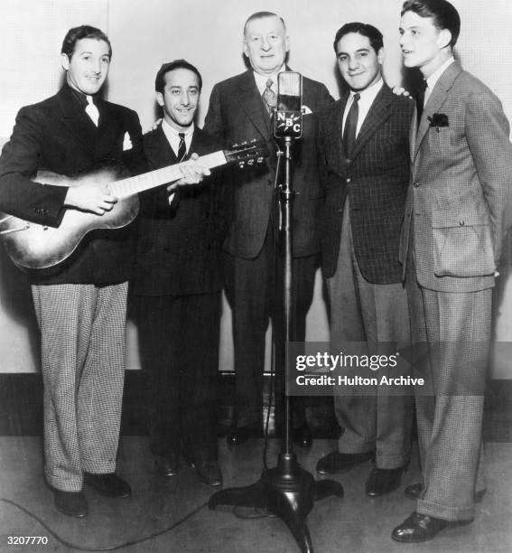 Full-length image of American actor and singer Frank Sinatra performing before a microphone with the Hoboken Four, NBC Studios.