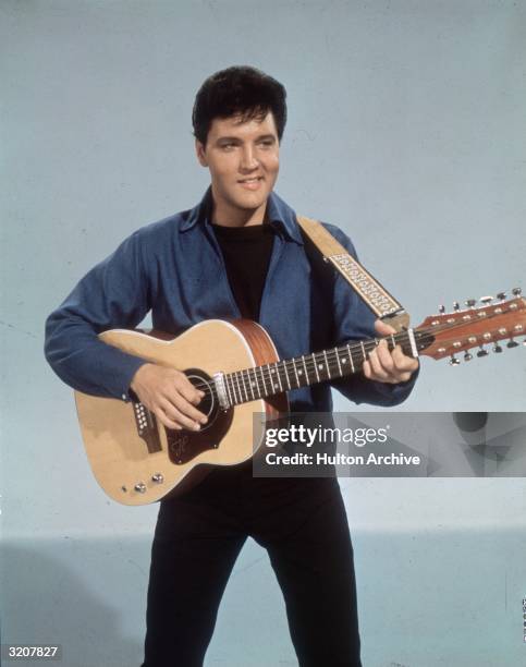 American rock 'n roll singer Elvis Presley with a twelve string guitar.