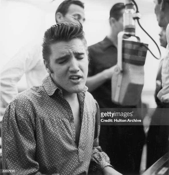 American Rock musician and actor Elvis Presley singing and playing the piano during a recording session for RCA.